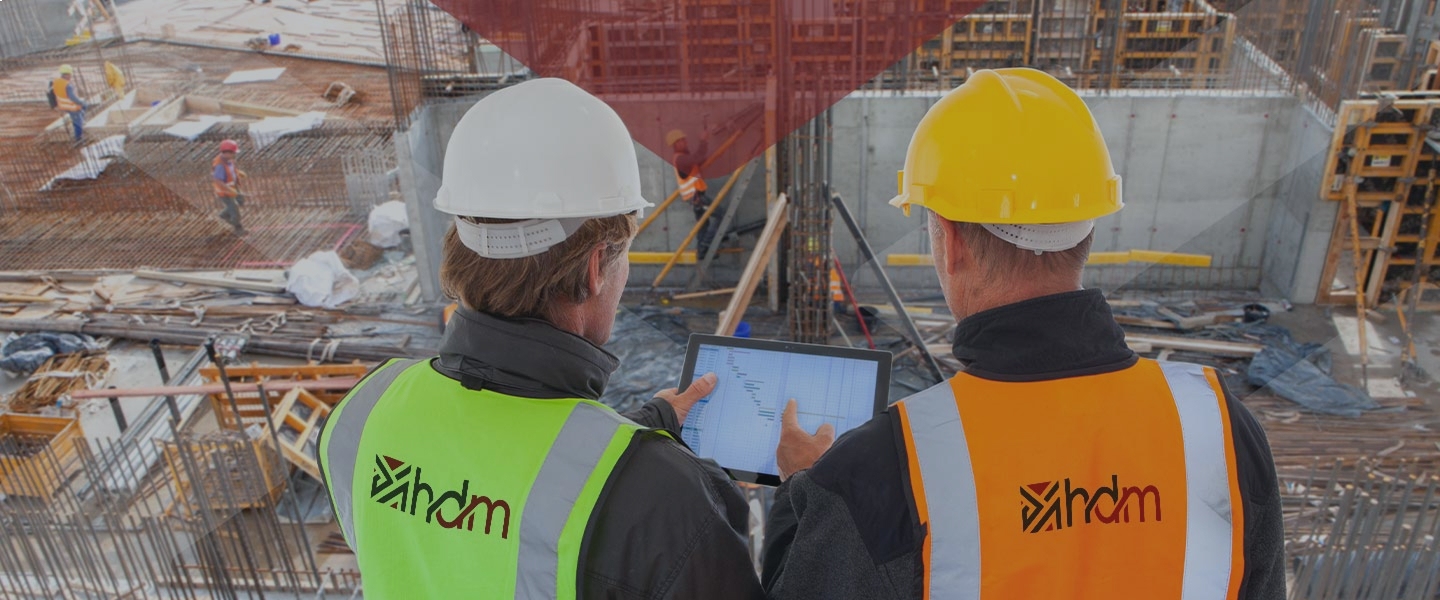Ingénieurs HDM en gilets sur chantier consultant un planning sur tablette